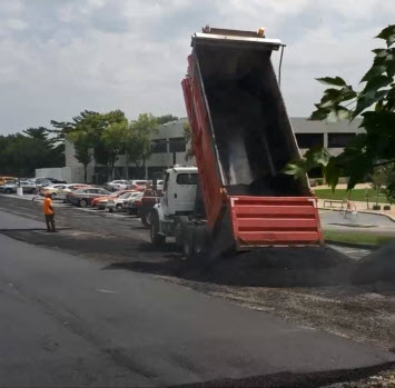 Paving contractor dumping hot asphalt on parking lot in St Louis MO